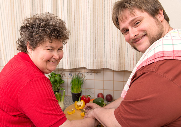 two people are cooking and smiling